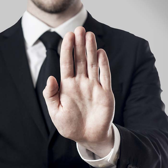 Man in a black suit with his hand held up in a stop gesture